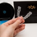 Hand holding clear aligners in a protective case showing modern clear aligners for orthodontic care