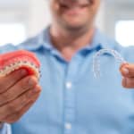 Orthodontist holding a braces model and a clear aligner while explaining orthodontic tips Mercer Island families can follow