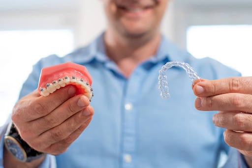 Orthodontist holding a braces model and a clear aligner while explaining orthodontic tips Mercer Island families can follow