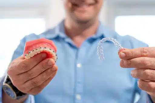 Orthodontic Tips Mercer Island Families Can Use Every Day Orthodontist holding a braces model and a clear aligner while explaining orthodontic tips Mercer Island families can follow