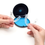 Hands holding a set of Clear Aligners Issaquah trays in front of an orthodontic case