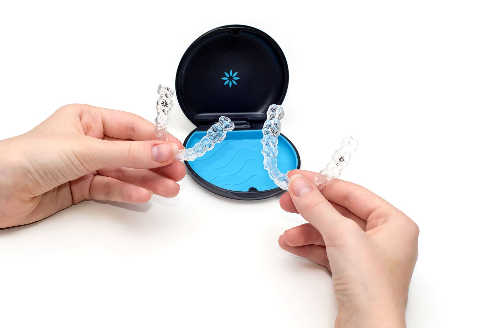 Hands holding a set of Clear Aligners Issaquah trays in front of an orthodontic case